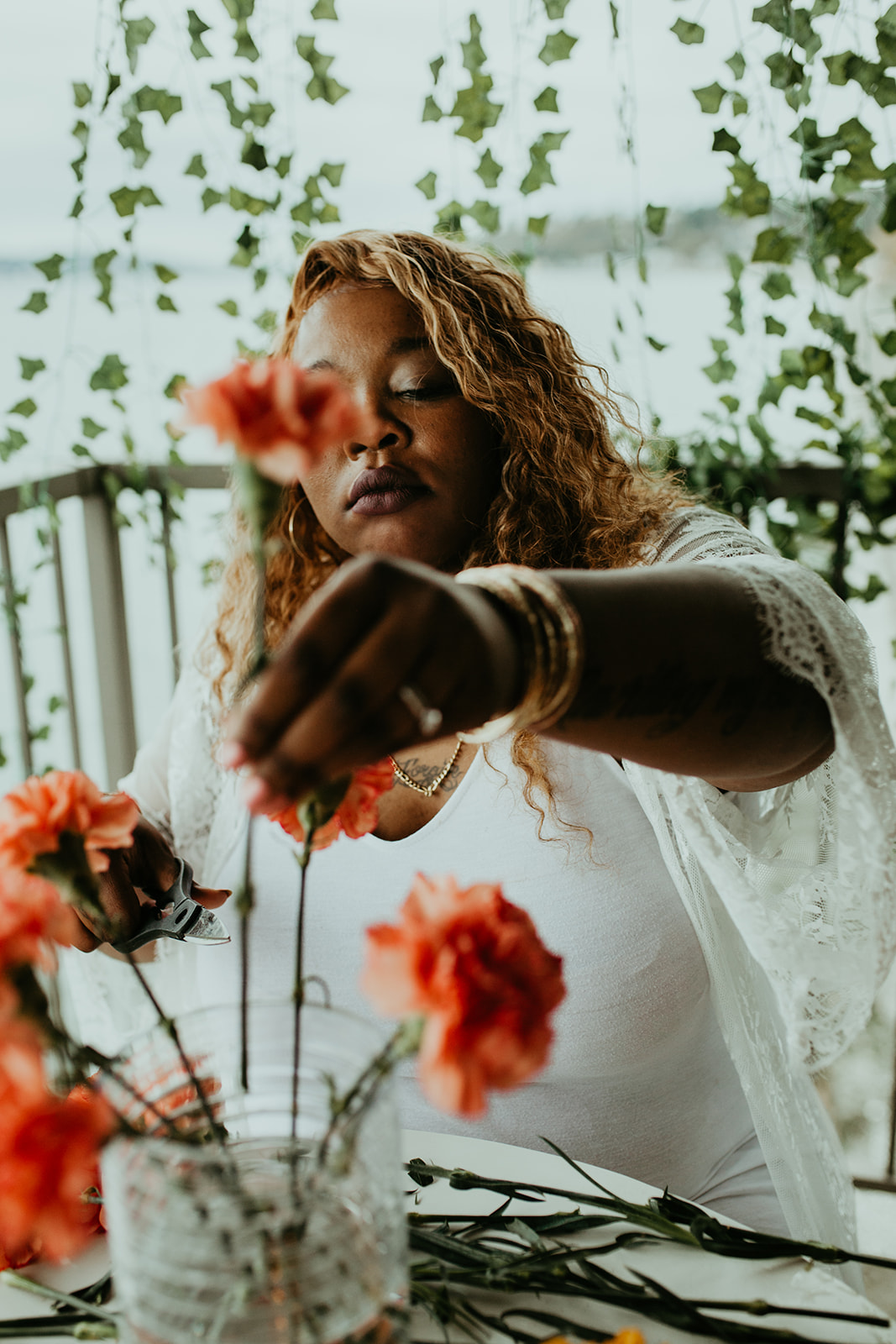 Rashida arranging coral carnations by the water