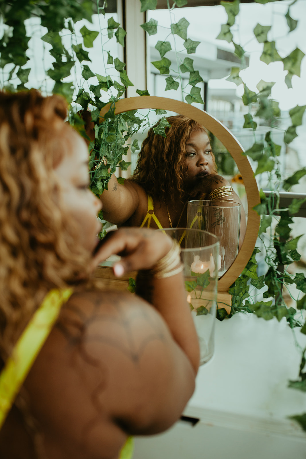 Rashida reflected in a round mirror surrounded by trailing ivy