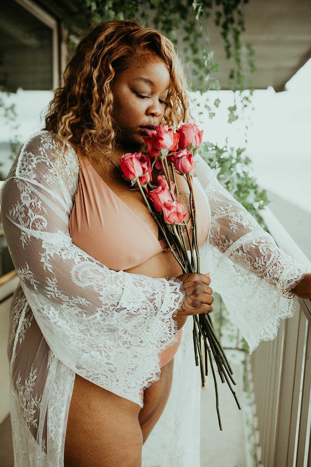 Rashida holding a bouquet of pink roses to her chest in lace